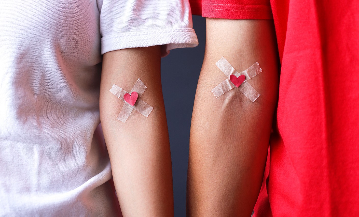 Arme mit Verband und Herz nach der Blutspende Zwei Arme mit Verband und Herz nach der Blutspende