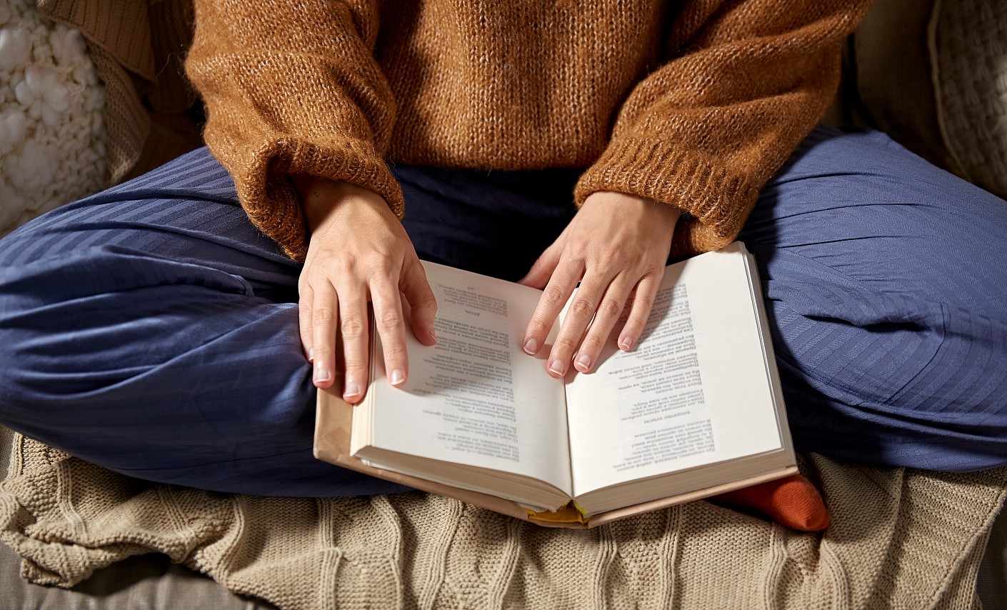 Ein Buch liegt auf dem Schoß einer Person im Schneidersitz