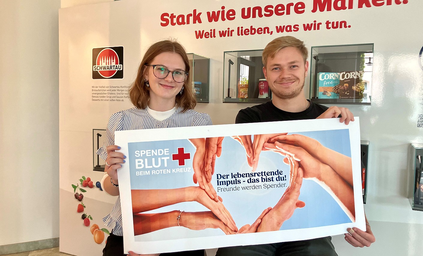 Mit-Organisatorin Emily hat ihren Ausbildungskollegen Magnus zu seiner Erstspende motiviert. Er freut sich darüber, nun seine eigene Blutgruppe zu erfahren blutspender-plakat-lächeln-sitzen